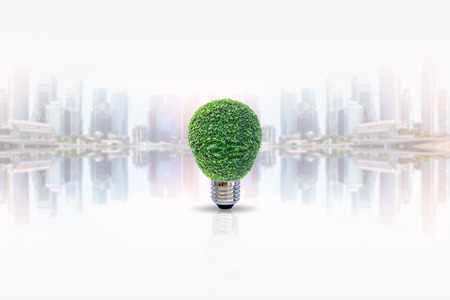Energy saving lamp of tree with shadow on blurred skyscraper background. Concept for saving energy, global warming, Earth Day, Go Green and save the world.の写真素材