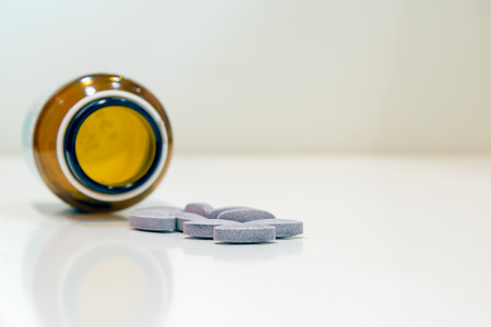 Closeup pills spilled from a bottle on white background.
