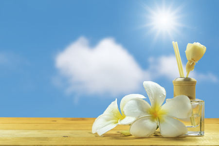 Bottle-conditioned with plumeria on the wooden floor with the blue sky background.の写真素材