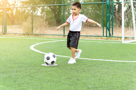 The boy was playing soccer on the football field with happiness.の写真素材