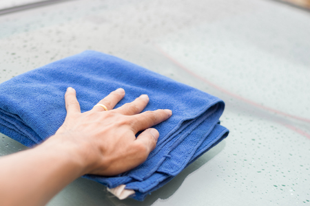 Wipe the rain drops on the roof of the car with a microfiber cloth.の写真素材