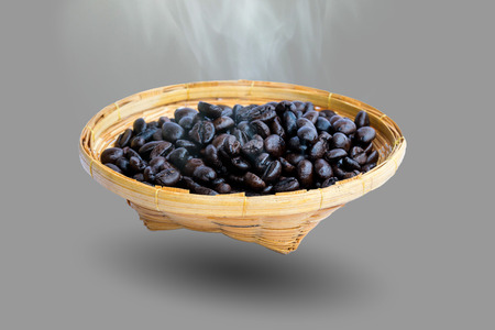 Hot coffee beans in the bamboo plate isolated on gray background.の写真素材