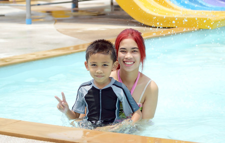 Asian boy and girl were sitting in the pool and smiling happily.の写真素材