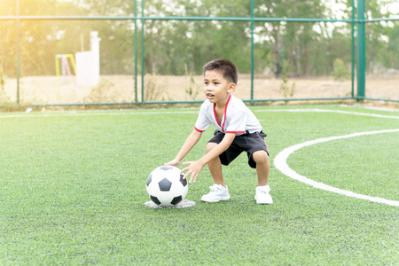 The boy was playing soccer on the football field with happiness.の写真素材