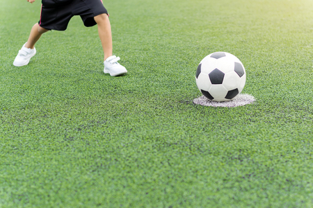 The boy was playing soccer on the football field with happiness.の写真素材