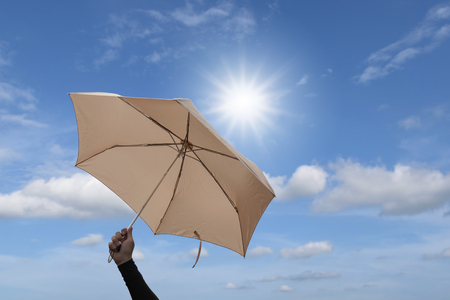 Hand are holding umbrella with blue sky and sunlight background.の写真素材
