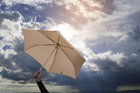 Hand holding umbrella with blue sky and sunlight background.の写真素材