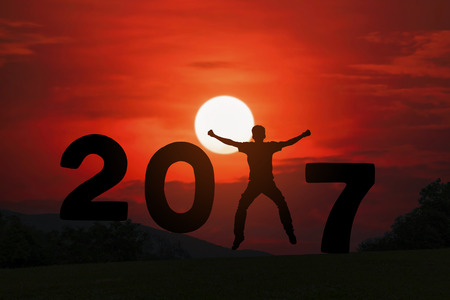 Silhouette of young man jumping between  2017 years with beautiful sunset.の写真素材