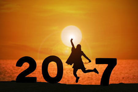 Silhouette of young woman jumping on the beach between 2017 years with beautiful sunset at the sea.の写真素材