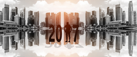 Silhouette of young man standing between 2017 years with beautiful blurred city background.の写真素材