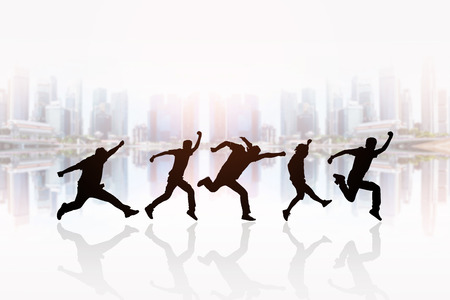 Silhouette of people running in front of the cityscape background.の写真素材