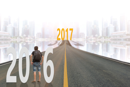 Young man standing on the street between 2016 years and looking to the 2017 years with the skyscraper background.の写真素材