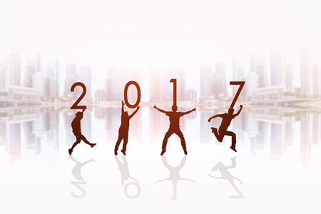 Silhouette of people holding numbers 2017 in front of the cityscape background, background for happy news years.の写真素材
