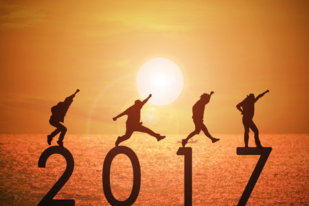 Silhouette group of young mans jumping on numbers 2017 over a beautiful sunset at the sea, background for happy news years.の写真素材