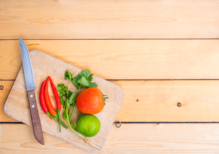 Various kinds of fresh vegetables for cooking on a wooden chopping board on a wooden floor.の写真素材