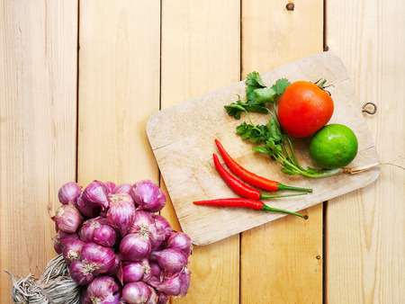 Various kinds of fresh vegetables for cooking on a wooden chopping board on a wooden floor.の写真素材