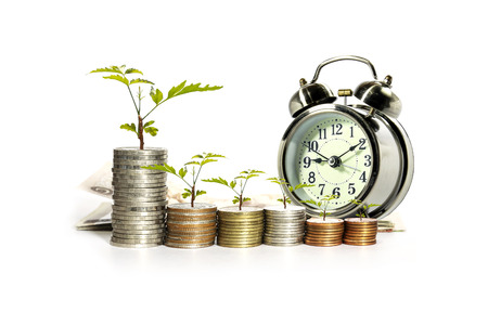 Young plant on coins with analog clock concept for saving moneys.の写真素材