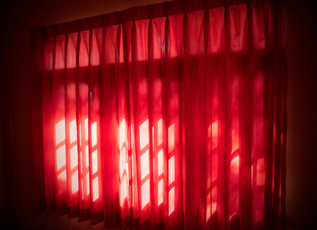 The red curtains covering the windows of a house or dwelling.の写真素材