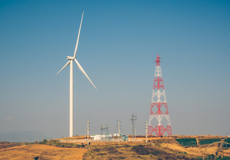 Wind turbine for electricity production on the mountains with high voltage pole.の写真素材