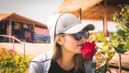 Asian women wearing caps and sunglasses are sniffing roses.の写真素材