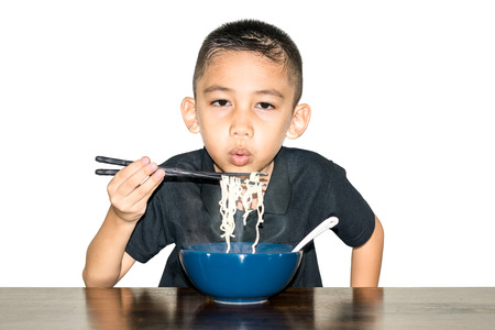 Asian boy wearing a black shirt is using chopsticks, noodles in a blue ceramic cup and cooled to eat-Fast food & Beverage concepts.の写真素材
