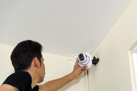Technicians are installing a wireless cctv camera on the roof, can connect to the Internet, and control the camera via a smartphone or tablet.の写真素材