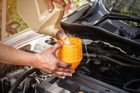 The car mechanic is adding oil to the engine, Automotive industry and garage concepts.の写真素材