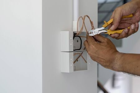 Technicians are using pliers to cut wires to install plugs and switches on the front door.の写真素材