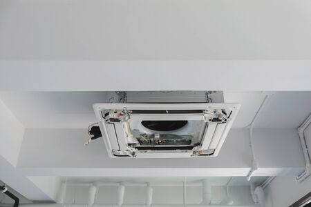 Four-way air conditioner mounted on the ceiling of the room, used for home or office.の写真素材