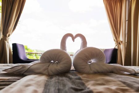 The white towel that was sculpted into a double goose is placed in the bed in the hotel bedroom.の写真素材