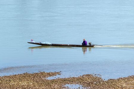 The long-tailed boat of fishermen is searching for fish in the Mekong River in Nong Khai province of Thailand.の写真素材