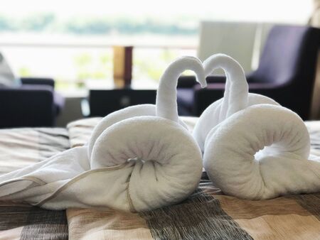 The white towel that was sculpted into a double goose is placed in the bed in the hotel bedroom.の写真素材