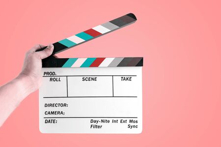 Hand of a man holding a cinema film slate isolated on pastel color background.の写真素材