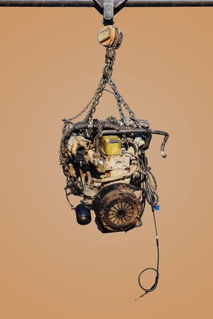 The old engine of the car hung on the hoist isolated on pastel color background, with clipping path.の写真素材
