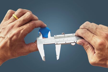 Closeup a 's  is using Vernier to measure the size of the plastic bottle cap isolated on pastel color background, with  .の写真素材