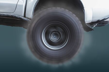 Closeup of the wheels of off-road vehicles that are rotating at high speed and with smoke coming out on pastel color background.の写真素材