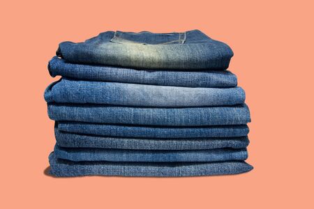 Stack of blue jeans long legs for men and women isolated on pastel color backgroundの写真素材