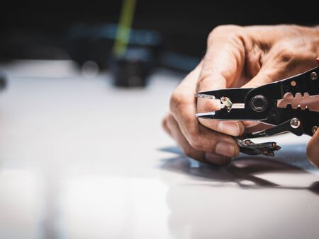 Closeup at the hand of an electrician is using electrical stripping pliers in industrial applications.の写真素材