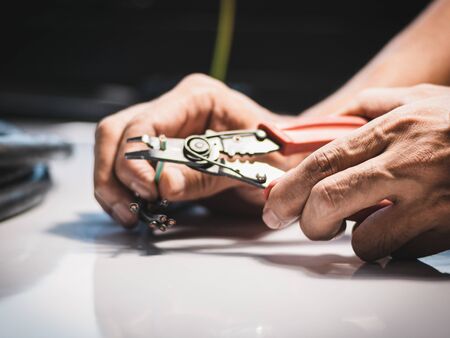 Closeup at the hand of an electrician is using electrical stripping pliers in industrial applications.の写真素材