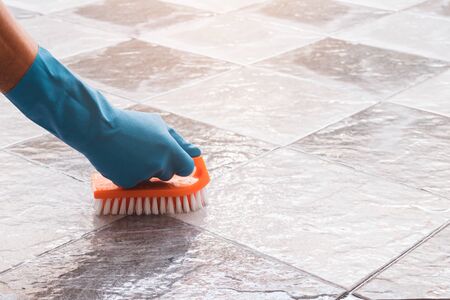 Hand of man wearing blue rubber gloves is used to convert scrub cleaning on the tile floor.の写真素材