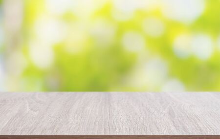 Tabletop made of wood with the blurred background of leaf bokeh, used for placing your products and objects.の写真素材