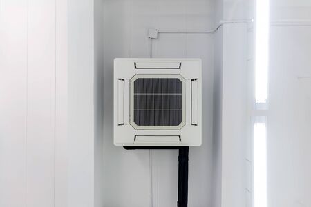 Four-way air conditioner mounted on the ceiling of the room, used for home or office.の写真素材