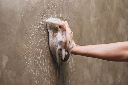 Hand of man using a sponge cleaning on the concrete wall.の写真素材