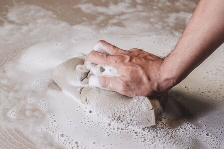 Hand of man  using a sponge cleaning the tile floor.の写真素材