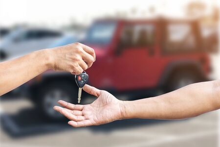 Closeup a man's hand is delivering a car key to another man's hand, use for the concept of car repair industry, insurance or automobile trading.の写真素材