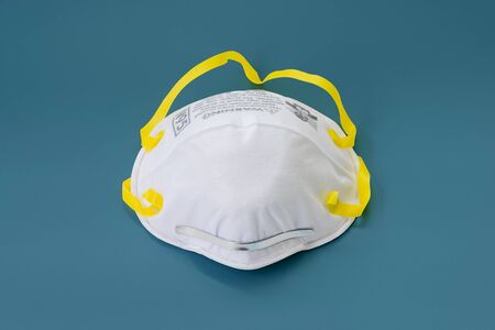 N95 mask respirator for dust, PM2.5, odor and chills. Coronavirus Covid-19 infection isolated on blue  pastel color  background.の写真素材