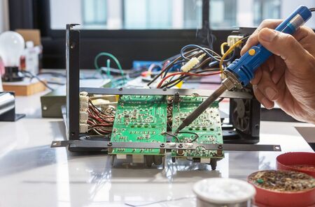 Electronic technician is soldering the electric wires to the motherboard of an electronic device.の写真素材