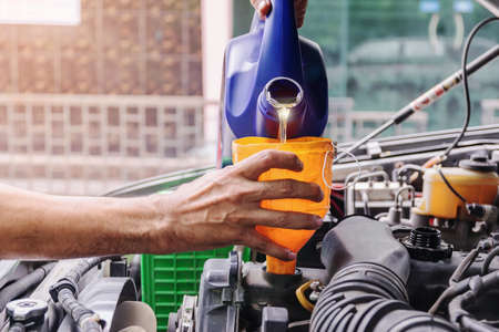 Car mechanic is adding oil to the engine, Automotive industry and garage concepts.の写真素材