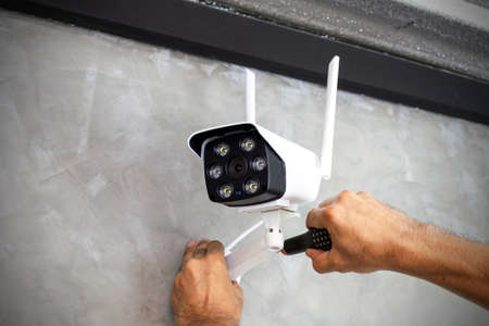 Technicians are installing wireless CCTV cameras on the walls of the house for security purposes.の写真素材