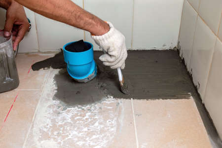 Construction workers are brushing waterproofing cement on tile floors in the bathroom.の写真素材